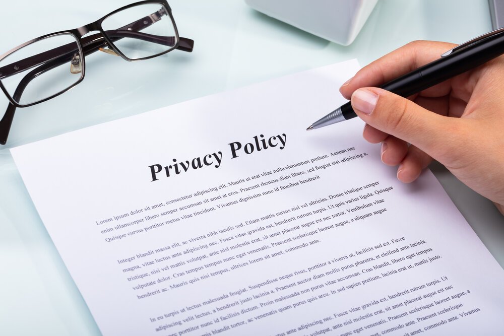 External Privacy Policy with hand hovering above it and reading glasses sitting on it